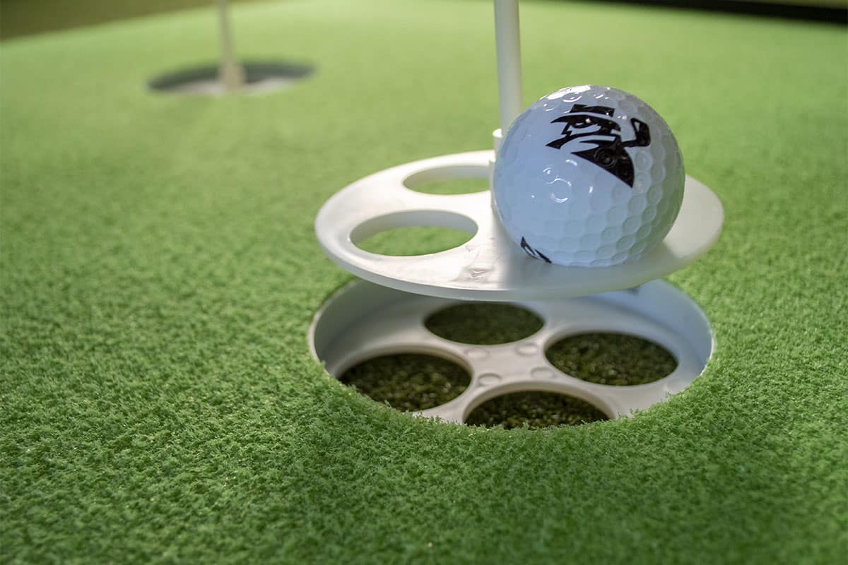 Pulling a ball out of a hole on one of the best indoor putting mats