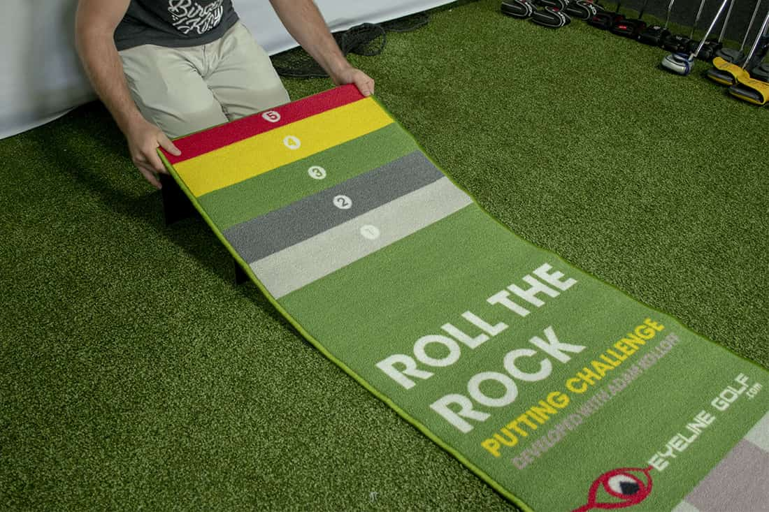 Someone rolling up one of the best indoor putting mats