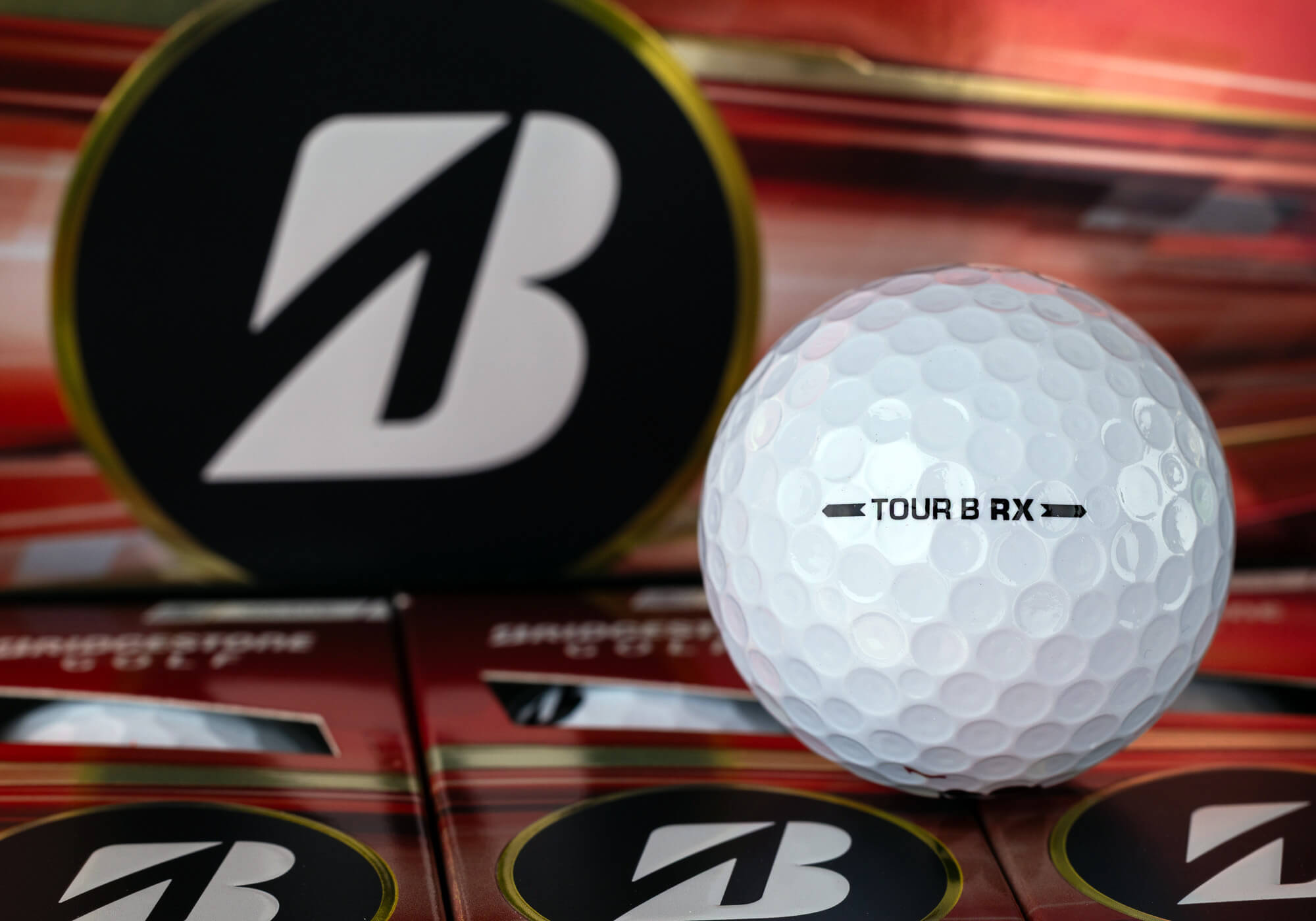 A Bridgestone TOUR B RX golf ball on red packaging