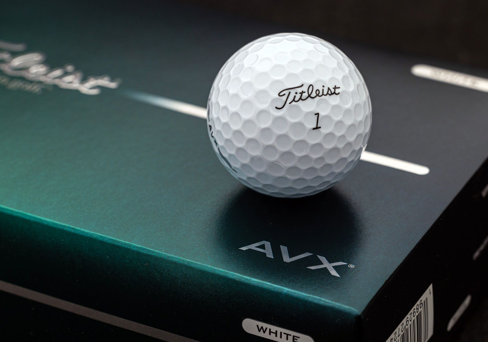 A number 1 titled AVX golf ball that rests on a case to show the AVX logo