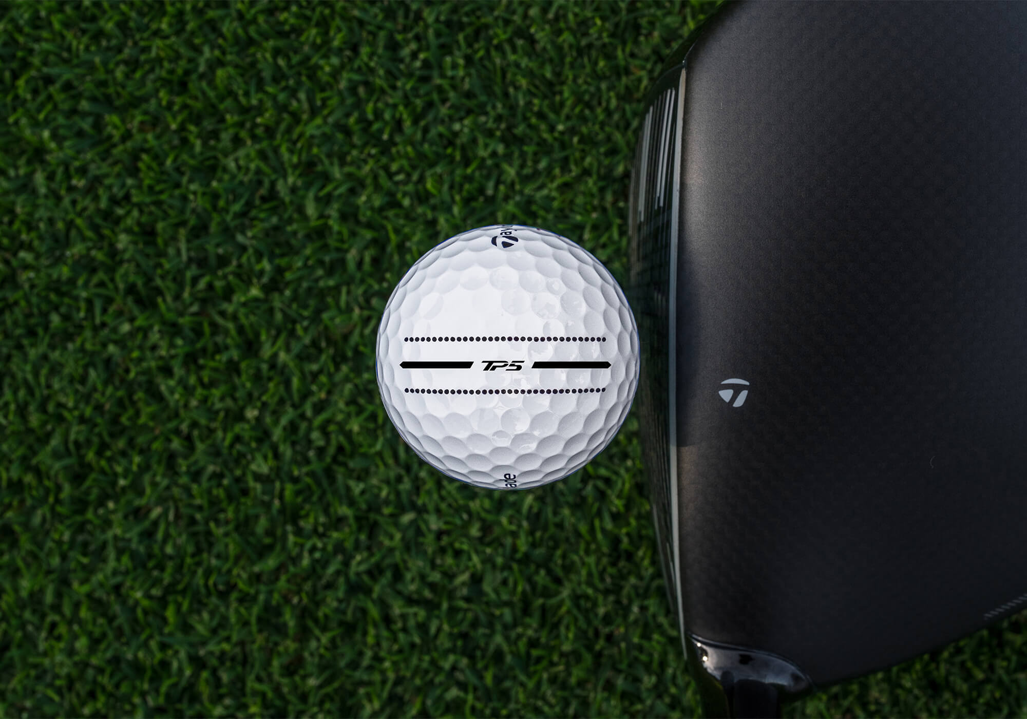 TaylorMade TP5 Performance Stripe against a driver face.